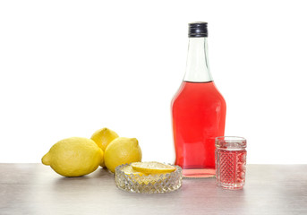 A bottle of liquor and lemons on the table close-up