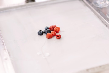 Naklejka na ściany i meble Berries on a thin sheet of white ice cream. Fresh blueberries and raspberries on a white sheet. Tasty dessert.
