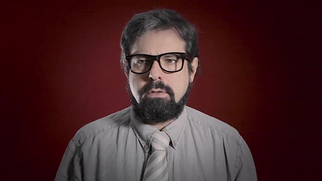 The expression of an alienated man. Medium close-up shot of the face over a red background. Part of a series of depictions of feelings and emotions with professional actors.