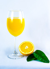 glass of orange juice, orange and orange leaves, on bright background