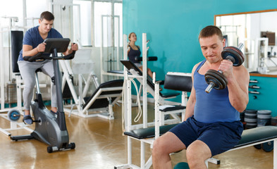 Fototapeta na wymiar Portrait of man lifting dumbbells at gym