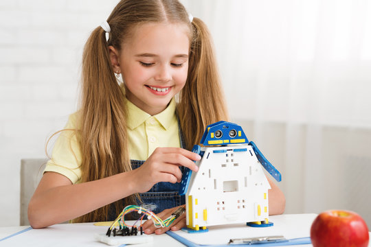 Modern technologies. Happy schoolgirl constructing robot, copy space