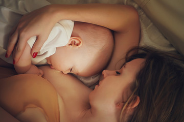 A young mother is breastfeeding a newborn baby. The view from the top.