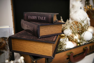 Fairy tale books that are on an open suitcase. A beautiful travel suitcase full of Christmas and New Year decorations.