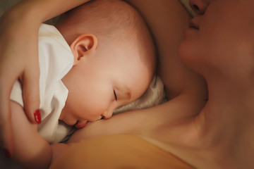 A young mother is breastfeeding a newborn baby. The view from the top.