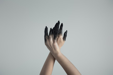 Cropped view of witch hands in black paint isolated on grey