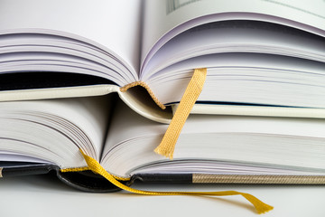 Two opened hardcover books with ribbon bookmarks. Isolated closeup on a white background..