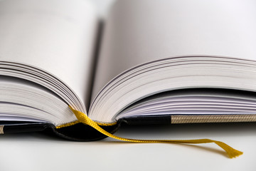 Opened blank hardcover book with ribbon bookmark. Isolated closeup on a white background.