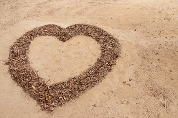Falling leaf in heart shape on soil background