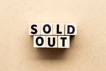 Letter block in word sold out on wood background