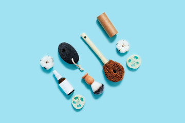 Zero waste concept. Craft tube, natural lotion in the spray glass bottle, shaver brush on blue background. Flat lay, top view, copy space.