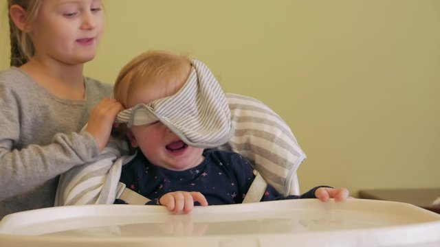 Little girl feeds brother puts on bib baby boy yogurt with spoon 6 and 1 year old caucasian europian white children