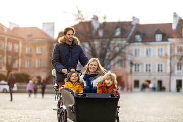 Young family enjoying spending time together, riding in a cargo bicycle