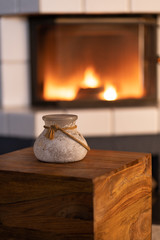 Glass vase with a cord on a wooden box in front of a blurred background with a fireplace, romantic scene