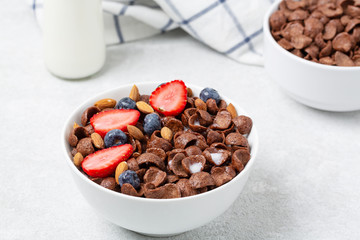 Chocolate flakes with fresh berries, milk and nuts in a bowl. Bowl of crispy chocolate flakes, milk, strawberries, blueberries and almonds. Delicious breakfast 