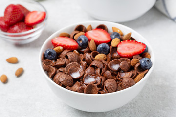 Chocolate flakes with fresh berries, milk and nuts in a bowl. Bowl of crispy chocolate flakes, milk, strawberries, blueberries and almonds. Delicious breakfast 