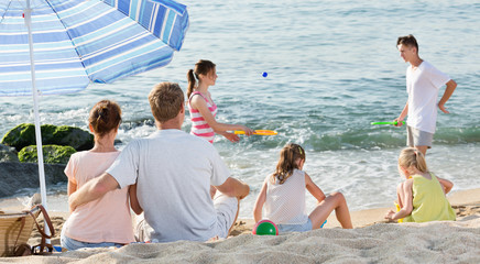 Parents and playing children on beach
