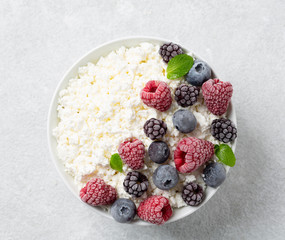 Cottage cheese with berries, honey and mint. Healthy breakfast cottage cheese with raspberries, blueberries and blackberries.