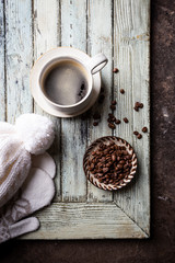 Top view cup of hot coffee with roasted coffee beans on wooden background. Winter composition.