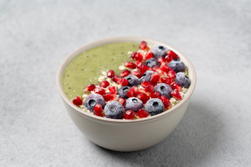 Healthy Breakfast detox green cocktail with kiwi, spinach, pomegranate, granola and blueberry berries in a bowl, vegan food.