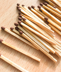 many wooden matches lie on a wooden background. flammable matches on a wooden table.