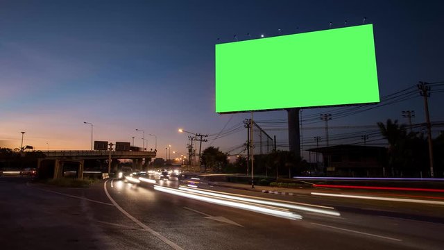 4k - Advertising billboard green screen on sidelines of expressway with traffic at evening, time lapse.