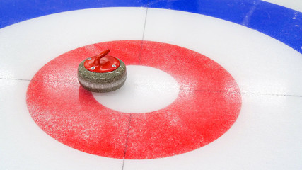 Curling winter, olympic sport.Curling stone and  Ice curling sheet with red and blue circle and visible pebbles 