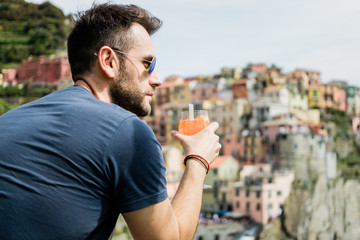 Young man drinking cocktail in village of Cinque Terre, Italy 