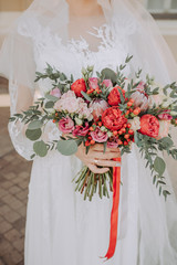 At the wedding, the bride and groom in beautiful clothes together hold the wedding bouquet in their hands
