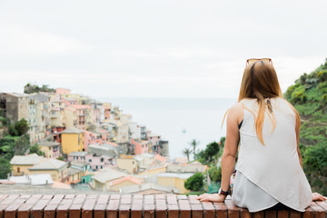 Fototapeta na wymiar Young woman enjoying panorama view of the village Cinque Terre by the sea