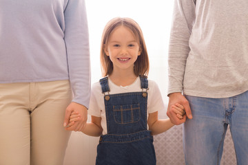 Portrait of cute little girl holding hands with her parents