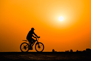 Obraz premium Silhouette man cycling on sunset background