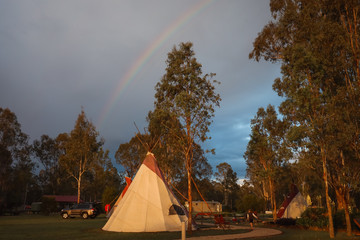 Tipi camp ground at sunset with rainbow