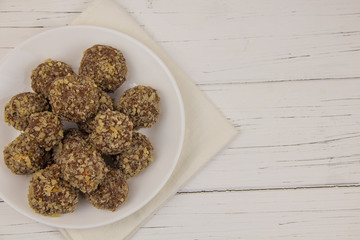 Energy balls homemade healthy candies without sugar in a white plate on a cotton napkin on a white wooden background
