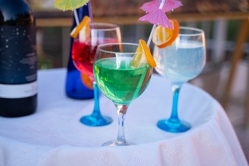 colorful cocktails with umbrellas and pieces of fruit are on the street on the table in a cafe in summertime  daylight