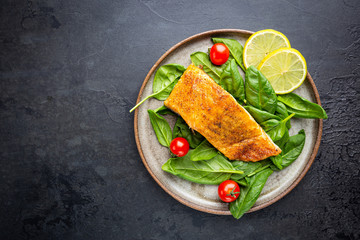 Grilled Spiced Salmon with fresh Spinach and Tomatoes Salad and Lemon Slices, top view