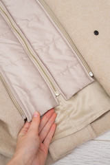 Clasp zip lining of a beige female coat close-up on a wooden background