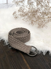 Gray twisted knitted belt on a wooden background