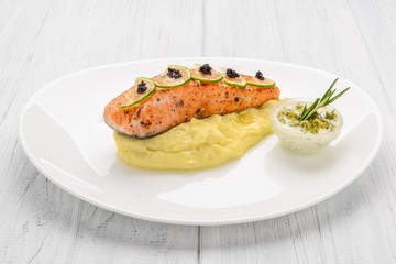 Grilled salmon, boiled potatoes and vegetables on a white plate