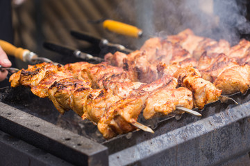Delicious bbq kebab grilling on open grill, outdoor kitchen. Food festival in city. Tasty food roasting on skewers, food-court. Summer picnic