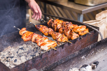 Delicious bbq kebab grilling on open grill, outdoor kitchen. Food festival in city. Tasty food roasting on skewers, food-court. Summer picnic