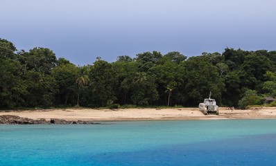 Vista de la Playa con mar azul y barco abandonado en isla del caribe