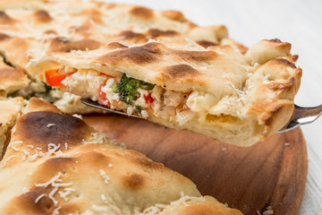 Pie with meat, vegetables and cheese on a wooden background