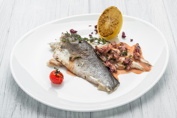 Baked sea bass with vegetables close up shoot on wooden background