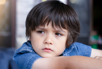 Emotional portrait of Unhappy Toddler boy with sad face, Upset boy standing alone looking out with...