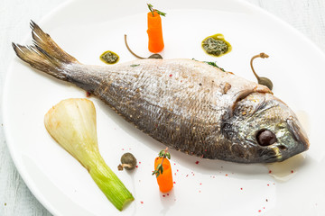 Grilled fish on platter isolated on white. Top view of whole roasted dorado