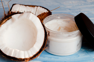  Coconut skin cream and two halves of coconut on a blue texture background