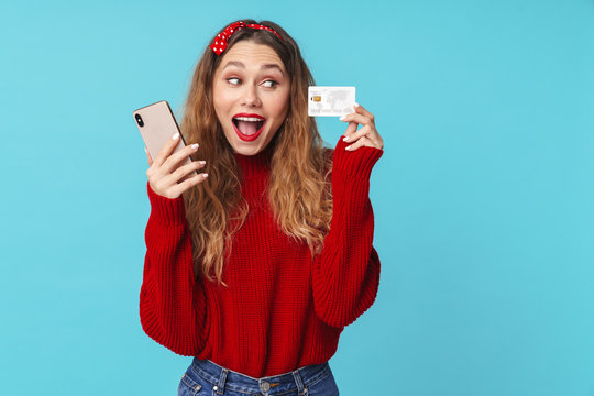 Image of excited blonde woman holding cellphone and credit card