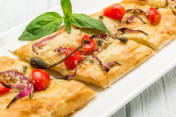 Puff-pizzas with mozzarella cheese, cherry tomatoes and baby basil.
