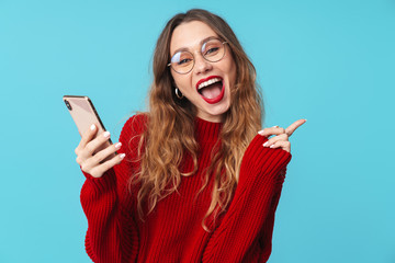 Image of delighted nice woman using cellphone and pointing finger aside